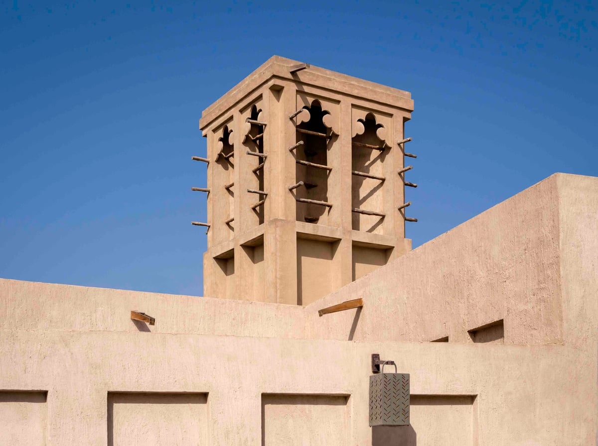 A coral-stone wind tower against a deep blue sky in the Al Shindagha quarter