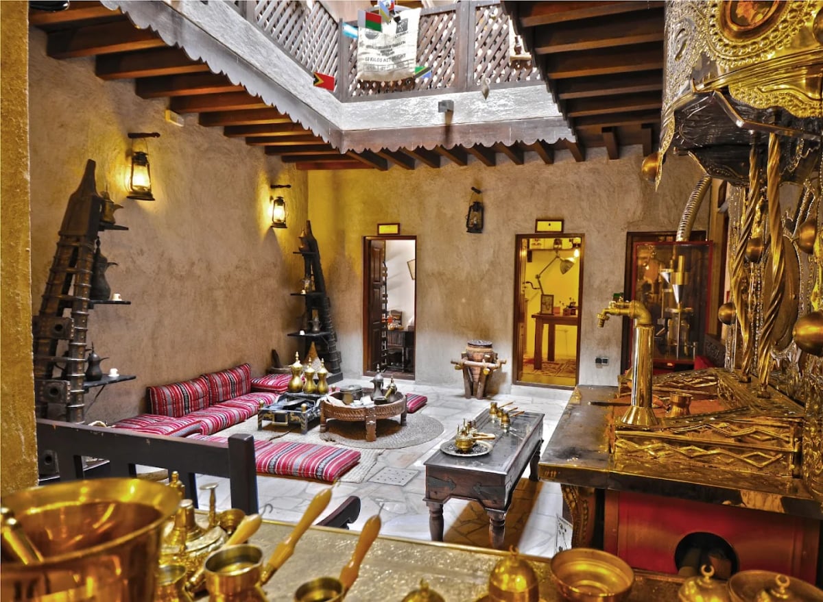 Brass coffee roasters and pots in front of a cushioned majlis