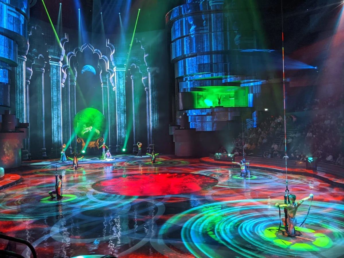Performers on a stage swirling with projected color and green lasers
