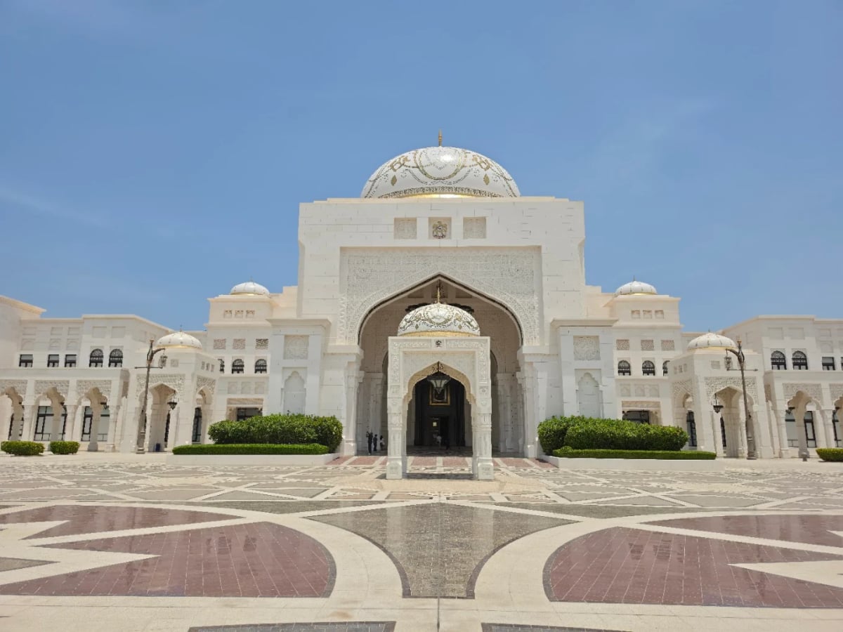 The white granite façade and central dome of Qasr Al Watan across a patterned marble forecourt