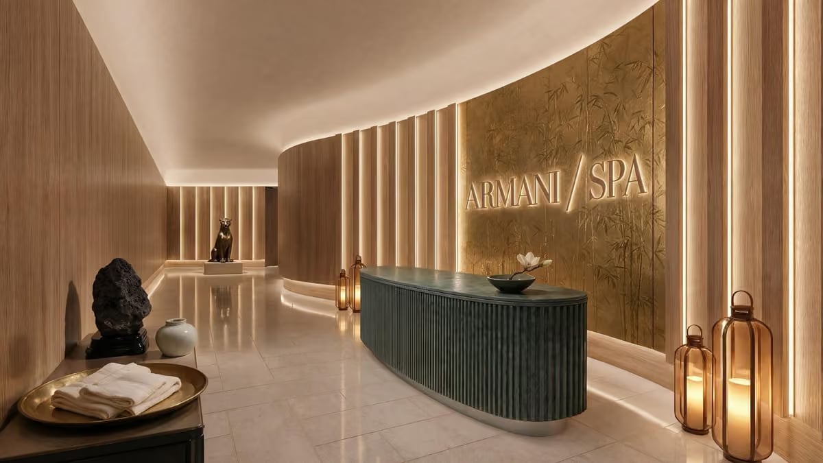 Reception desk of Armani/SPA at Armani Hotel Dubai, a curved wooden counter beneath the illuminated Armani/SPA wall lettering.