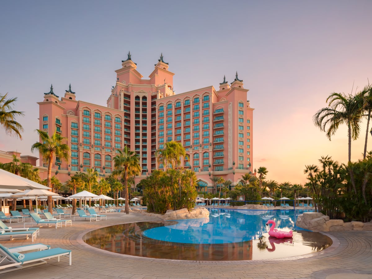 The family pool at Atlantis The Palm with a pink flamingo float, loungers and the hotel towers at sunset.