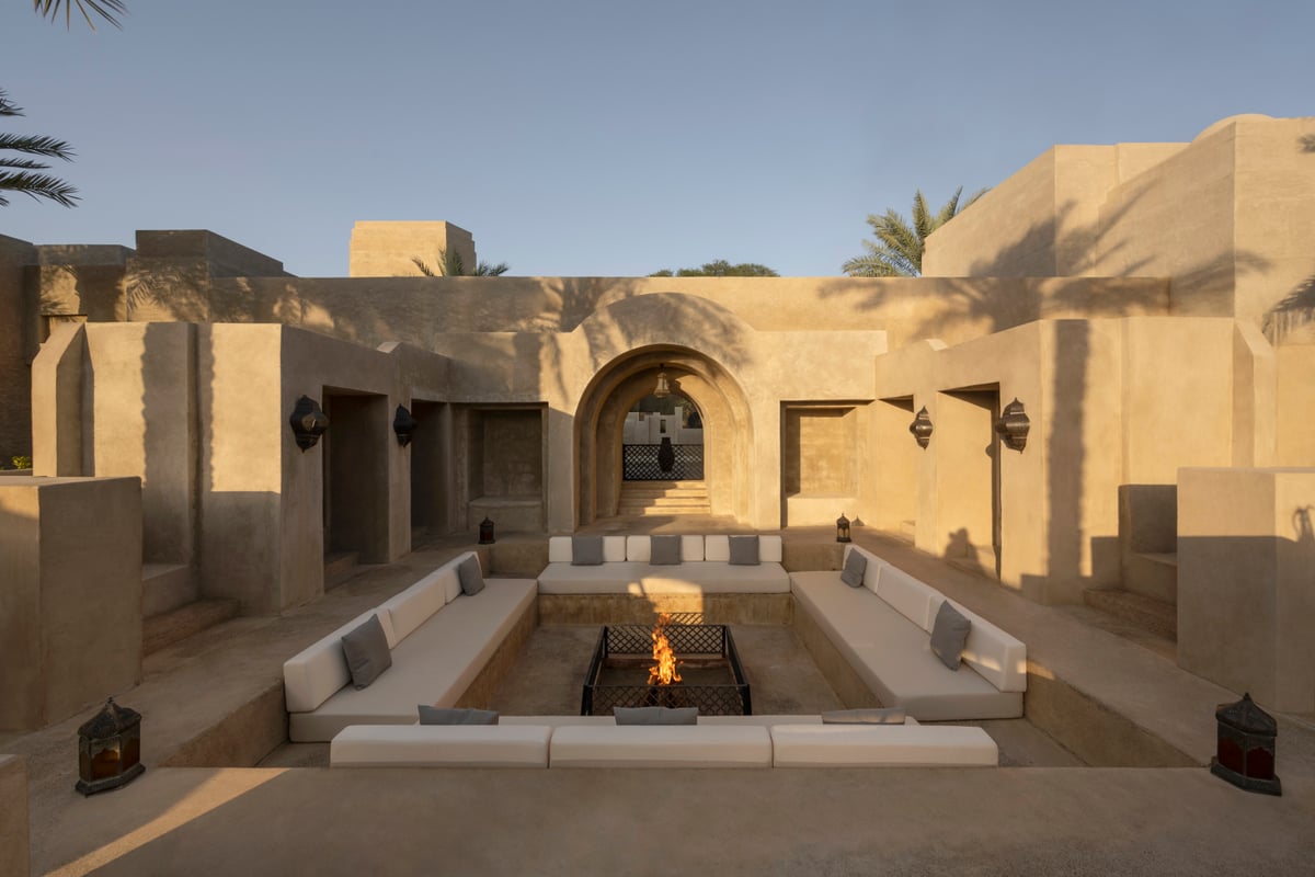 A sunken seating area around a lit fire pit in an earth-toned courtyard at Bab Al Shams.