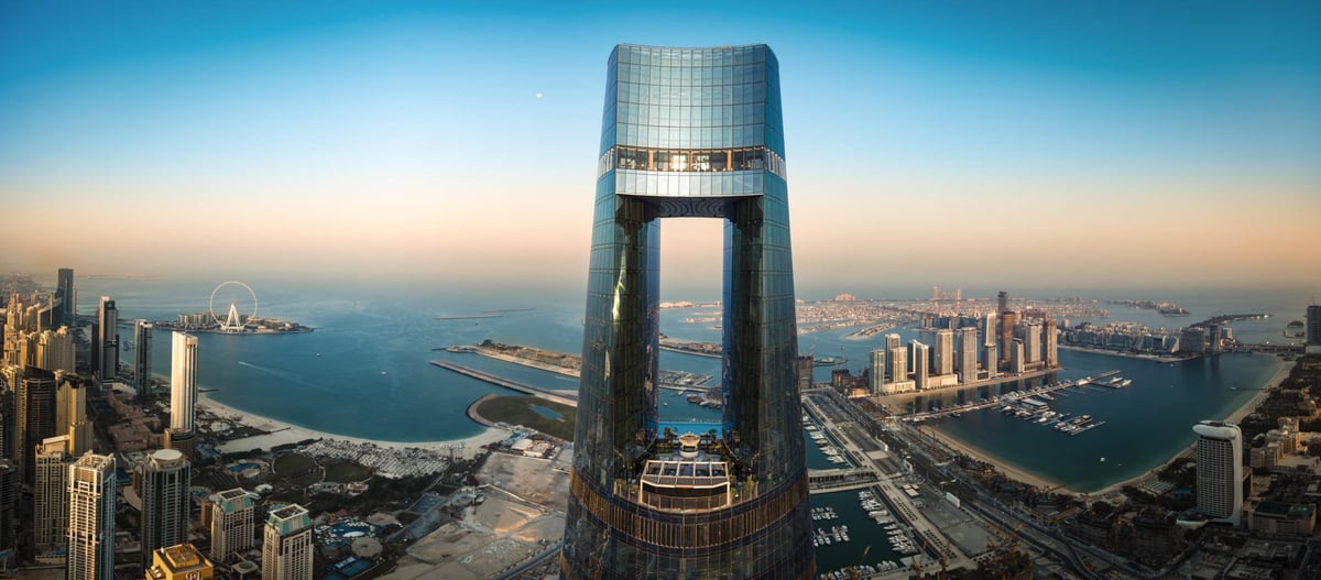 Wide daytime panorama with Ciel Dubai Marina at the center, between the marina towers and the Palm Jumeirah coastline.