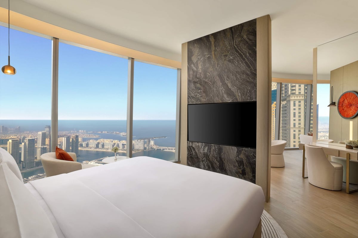 One Bedroom Suite, bed beside wide windows looking over the coast and towers, at Ciel Dubai Marina.