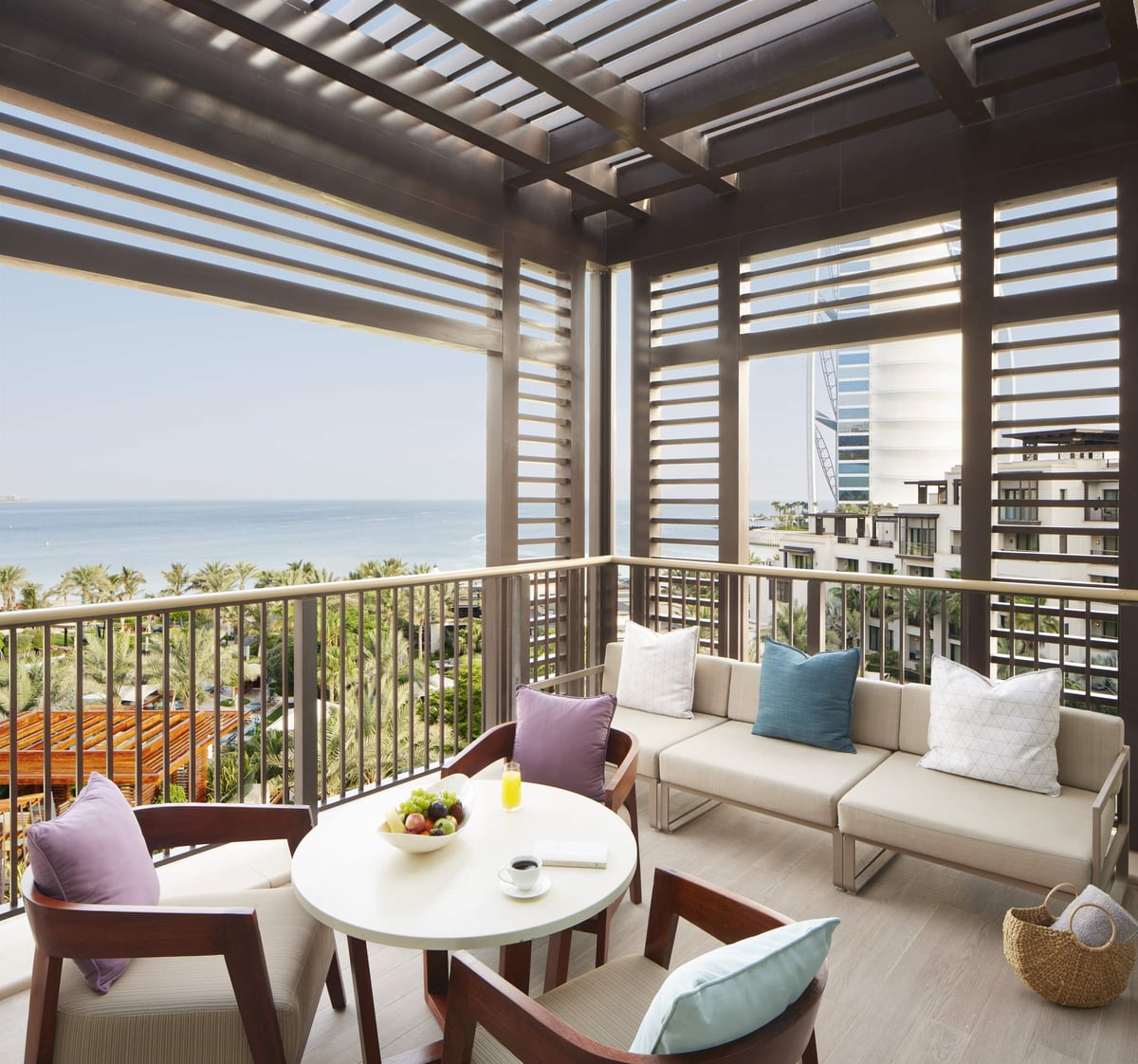 Family Suite, balcony with a sofa and round table overlooking palms and the sea, at Jumeirah Al Naseem.