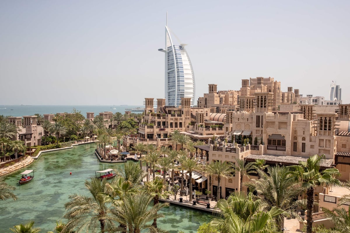 Madinat Jumeirah waterways with abras and wind-tower buildings, the Burj Al Arab rising behind, seen from Jumeirah Al Qasr.