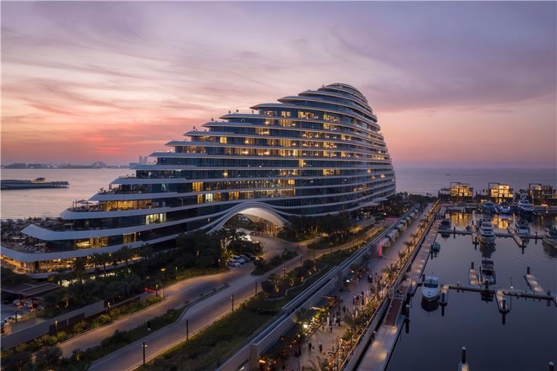 Jumeirah Marsa Al Arab lit at dusk above its marina and moored yachts