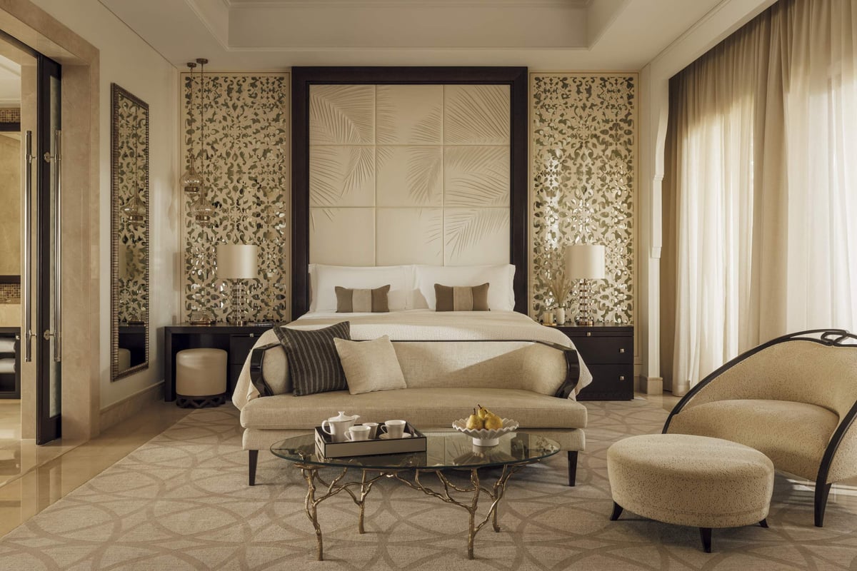 Three-Bedroom Villa, bedroom with a king bed, carved screens, curved armchairs and a glass coffee table, at One&Only The Palm.
