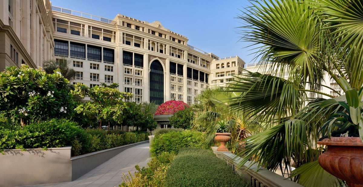 The hotel's façade rising above landscaped gardens and palms in morning light