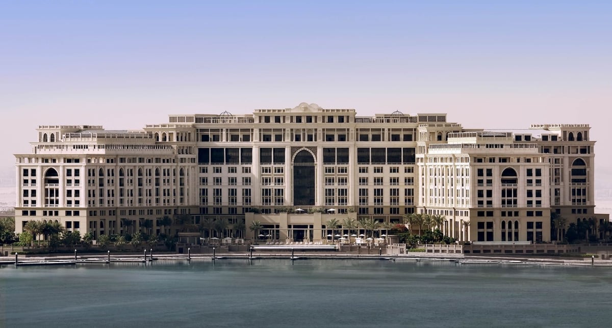 The long cream palace façade of Palazzo Versace Dubai across the water by day