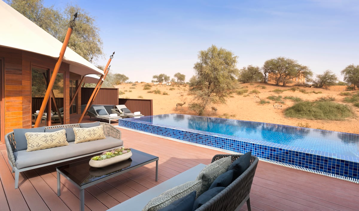 Al Khaimah Villa, pool deck with sofa and coffee table beside an infinity pool facing the dunes, at The Ritz-Carlton Al Wadi Desert.