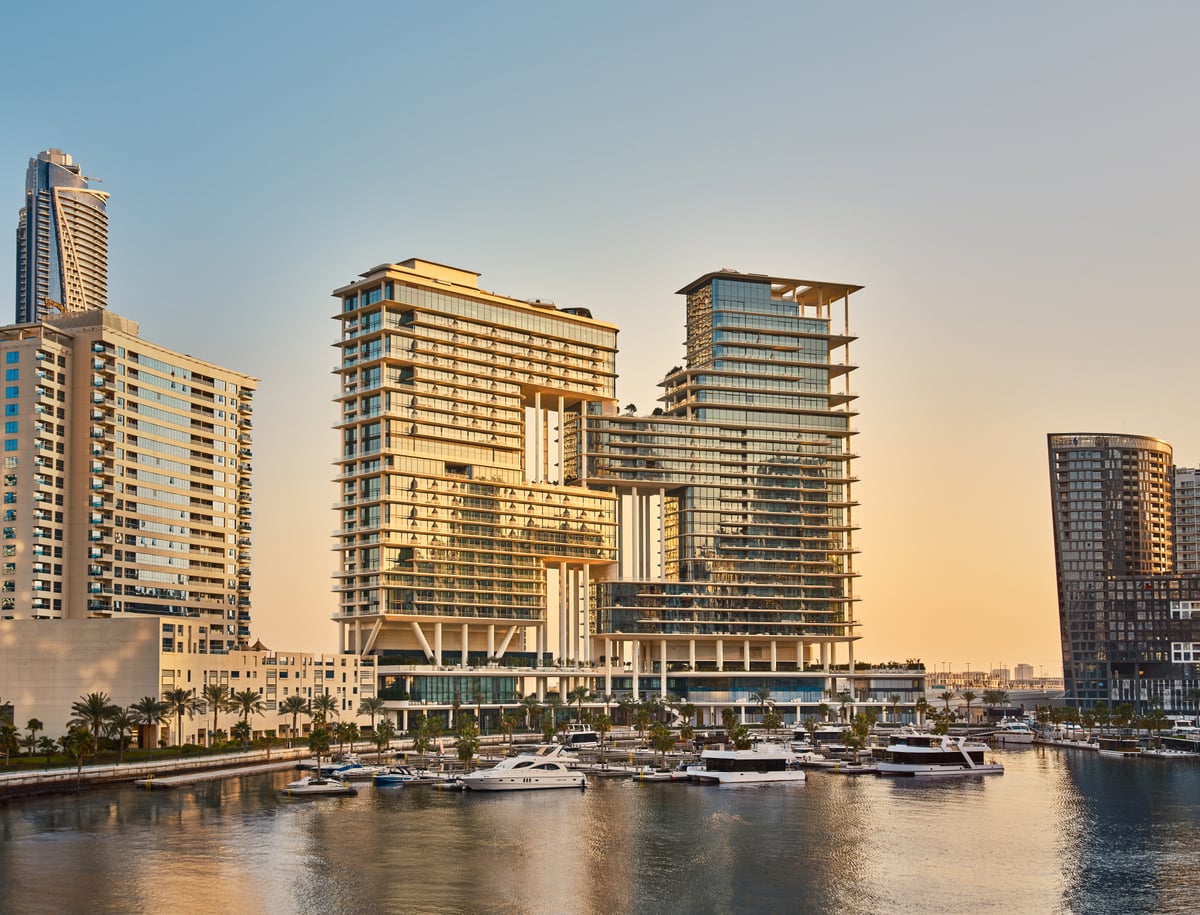 The Lana towers rising above the marina with yachts moored in front at golden hour.