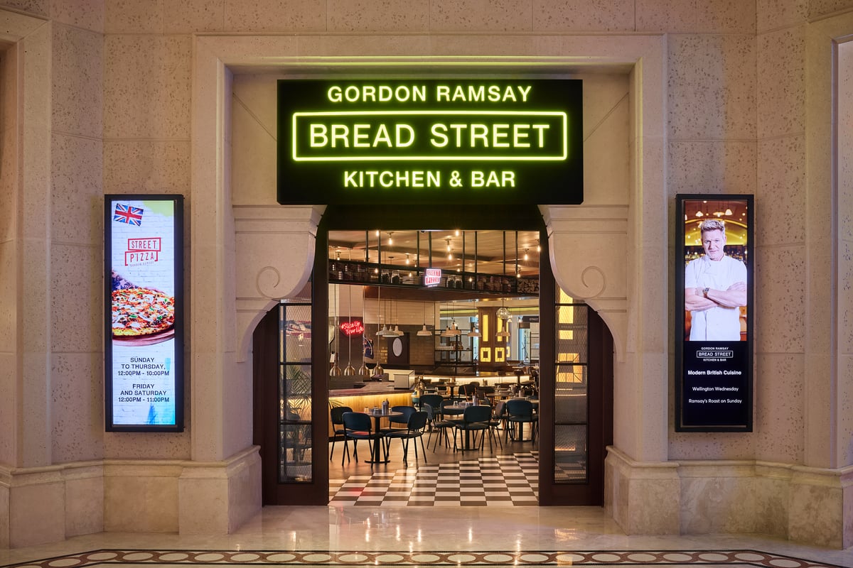 The neon Gordon Ramsay Bread Street Kitchen & Bar sign over an arched entrance, the checkerboard-floored restaurant visible inside