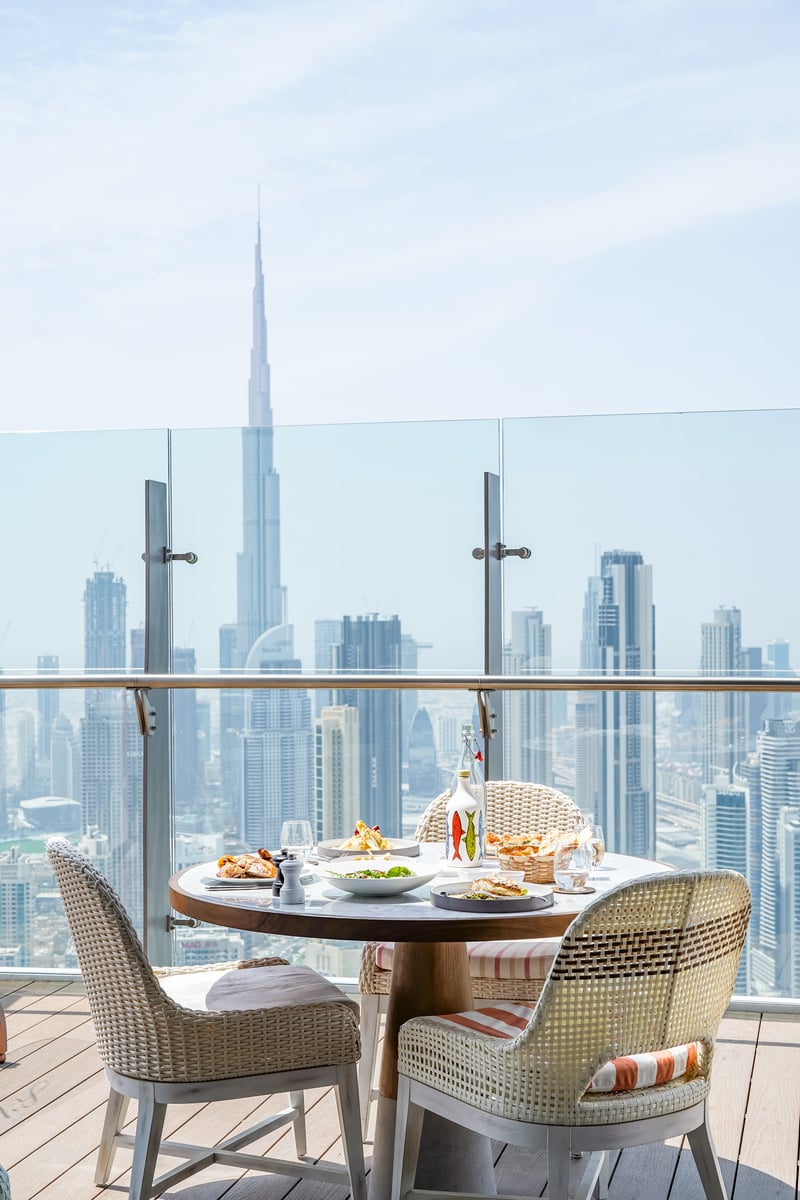 A terrace table for two set against the glass, the Burj Khalifa and Downtown skyline behind