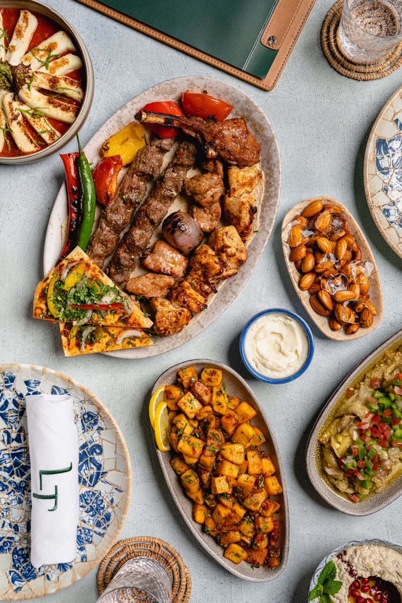 A mixed grill of kebabs and grilled vegetables surrounded by spiced potatoes, halloumi and dips