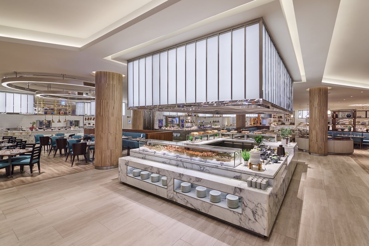 A marble buffet island under a glowing white lantern canopy at the center of the dining room
