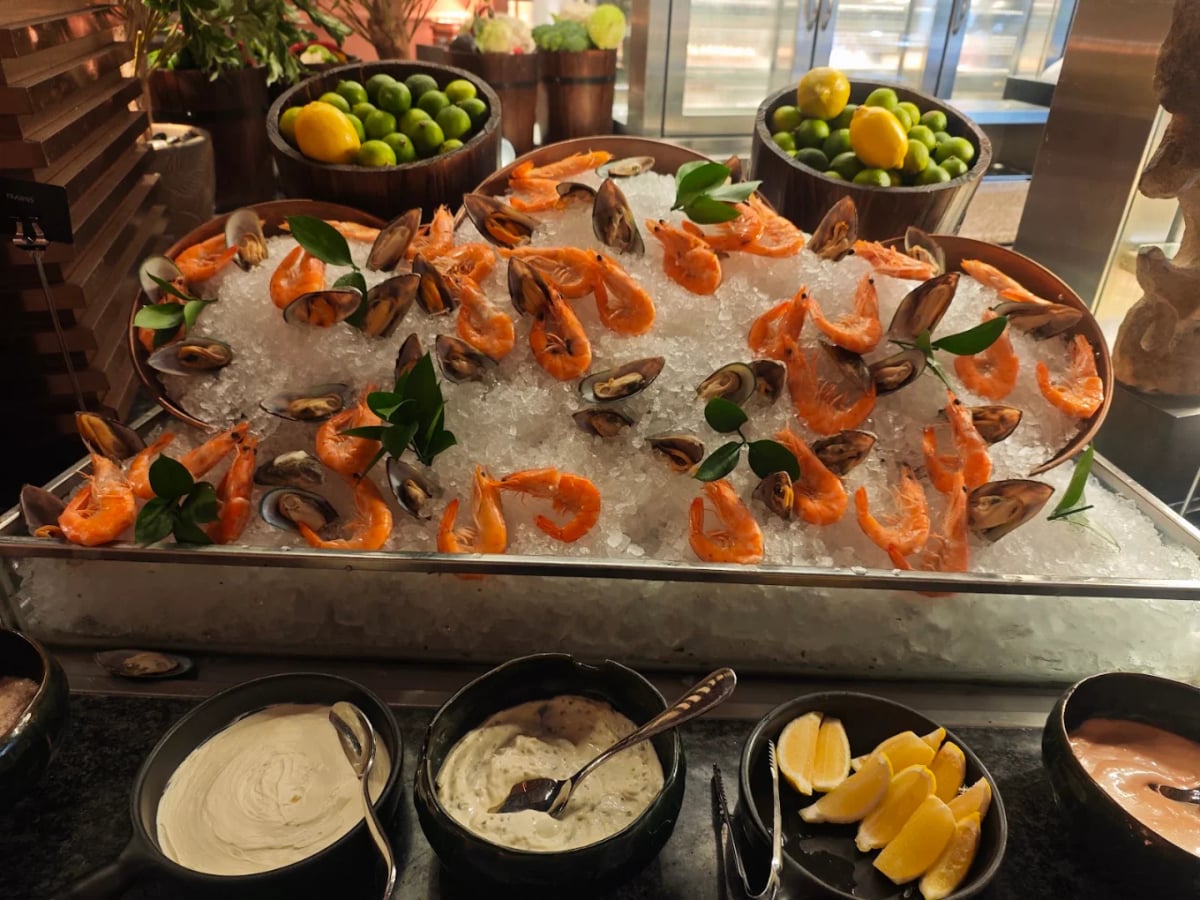 Prawns and mussels piled on crushed ice at the buffet, sauces and lemon wedges in front