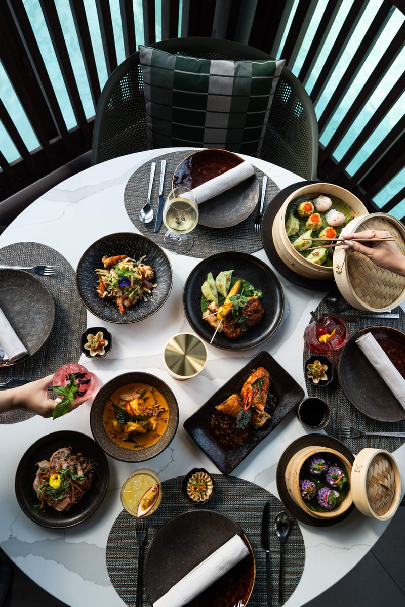 A round table seen from above set with curries, salads, dim sum baskets and rice for sharing